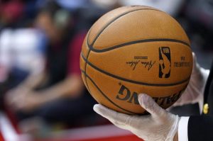 A security guard wears gloves while holding a basketball during halftime of an NBA game in Houston on March 5, 2020. The NBA has told players to avoid high-fiving fans and to avoid taking any item for autographs. AP Photo/David J. Phillip